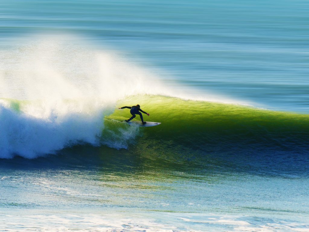 Surfeur professionnel dans une vague avec sa planche de surf
